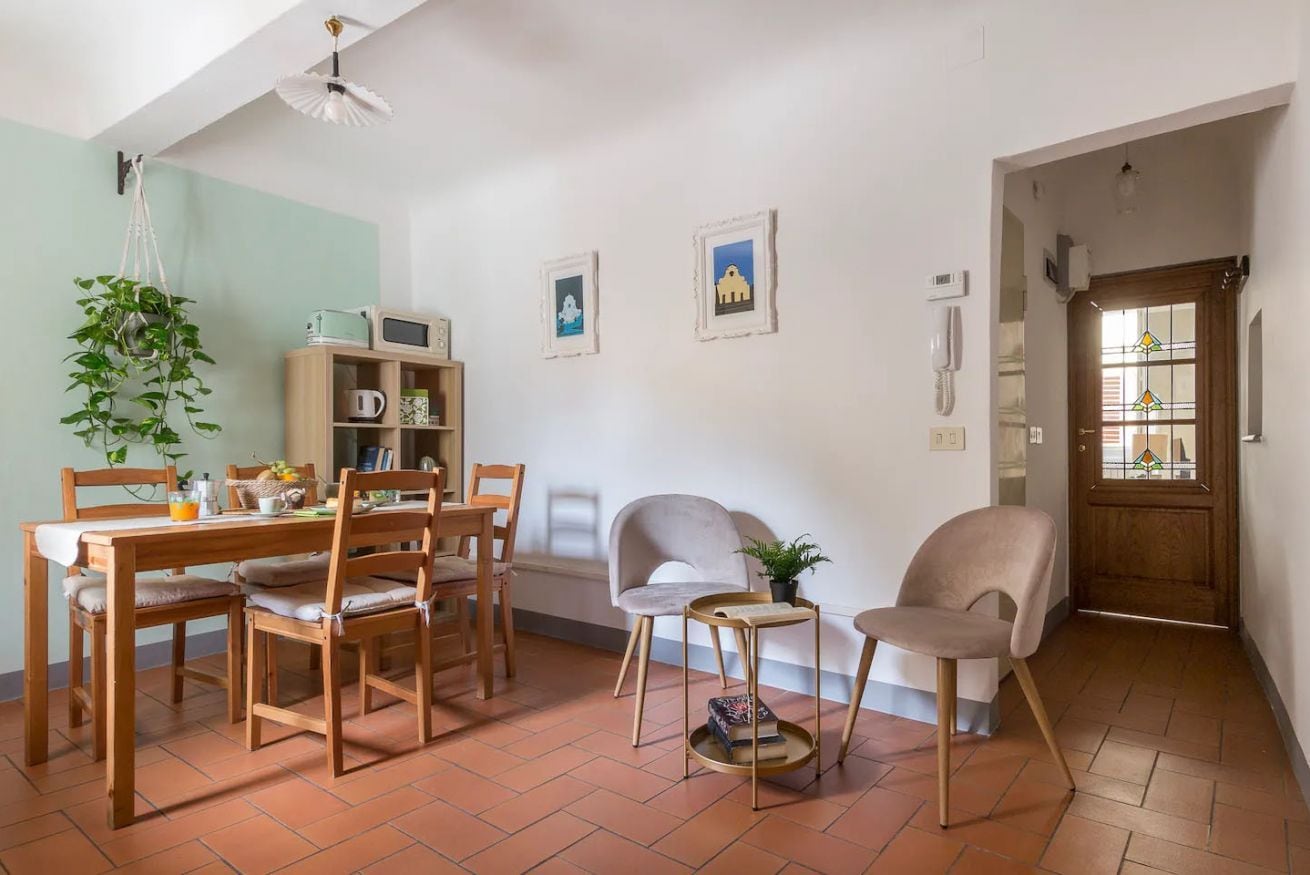A dining area with a wooden table, chairs, a hanging plant, and a small side table.