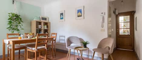 A dining area with a wooden table, chairs, a hanging plant, and a small side table.