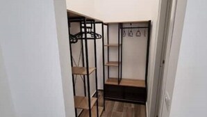 Et rummeligt opbevaringsskab med flere hylder og mulighed for at hænge tøj, sandsynligvis til opbevaring af bagage eller personlige ejendele.