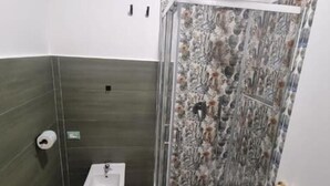 Et badeværelse med brusekabine, vask og toilet.