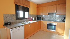 A kitchen with wooden cabinets, a dishwasher, a microwave, and an oven.