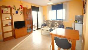 A compact living space with a TV, wooden furniture, a sofa, and a dining area.