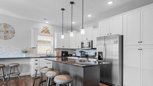 A modern kitchen with white cabinets, stainless steel appliances, and a central island with bar stools.
