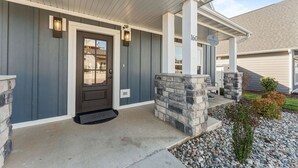 A house with a dark front door, stone pillars, and a number '160' sign.