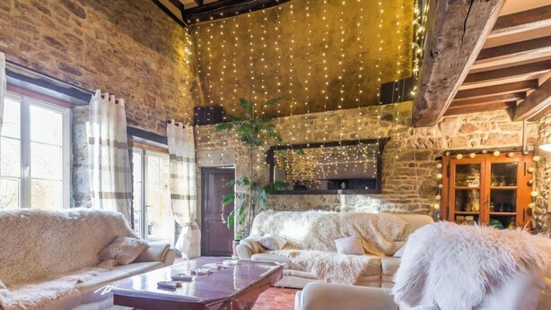 Une pièce chaleureuse avec des murs en pierre, une cheminée, un canapé et une table basse.