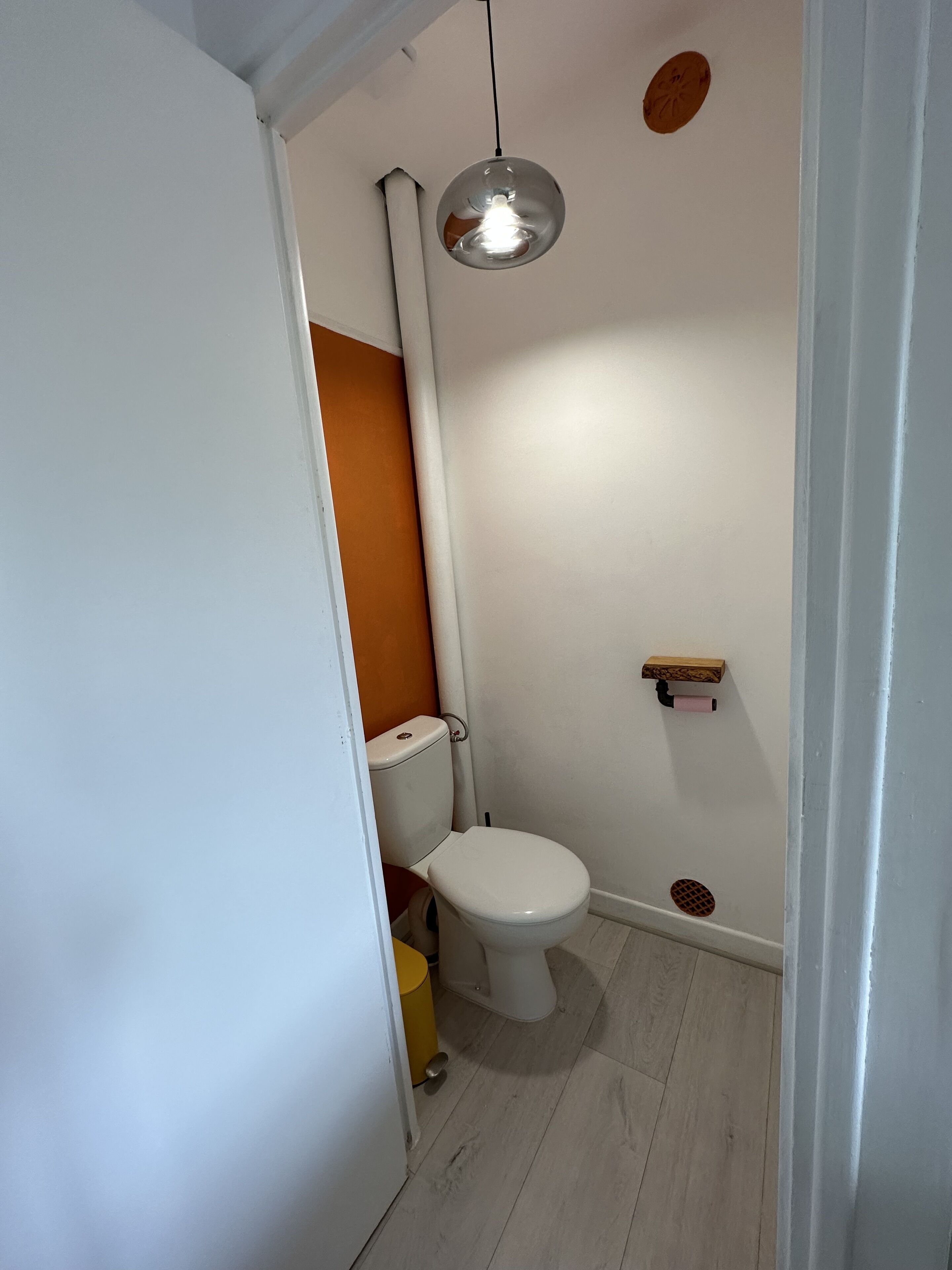 A small, clean bathroom with a toilet, a sink, and a hanging light fixture.