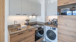 A modern kitchen with wooden cabinets, a built-in oven, a washing machine, and a toaster. - Bright apartment with terrace and parking in Alpe d'Huez (Huez)