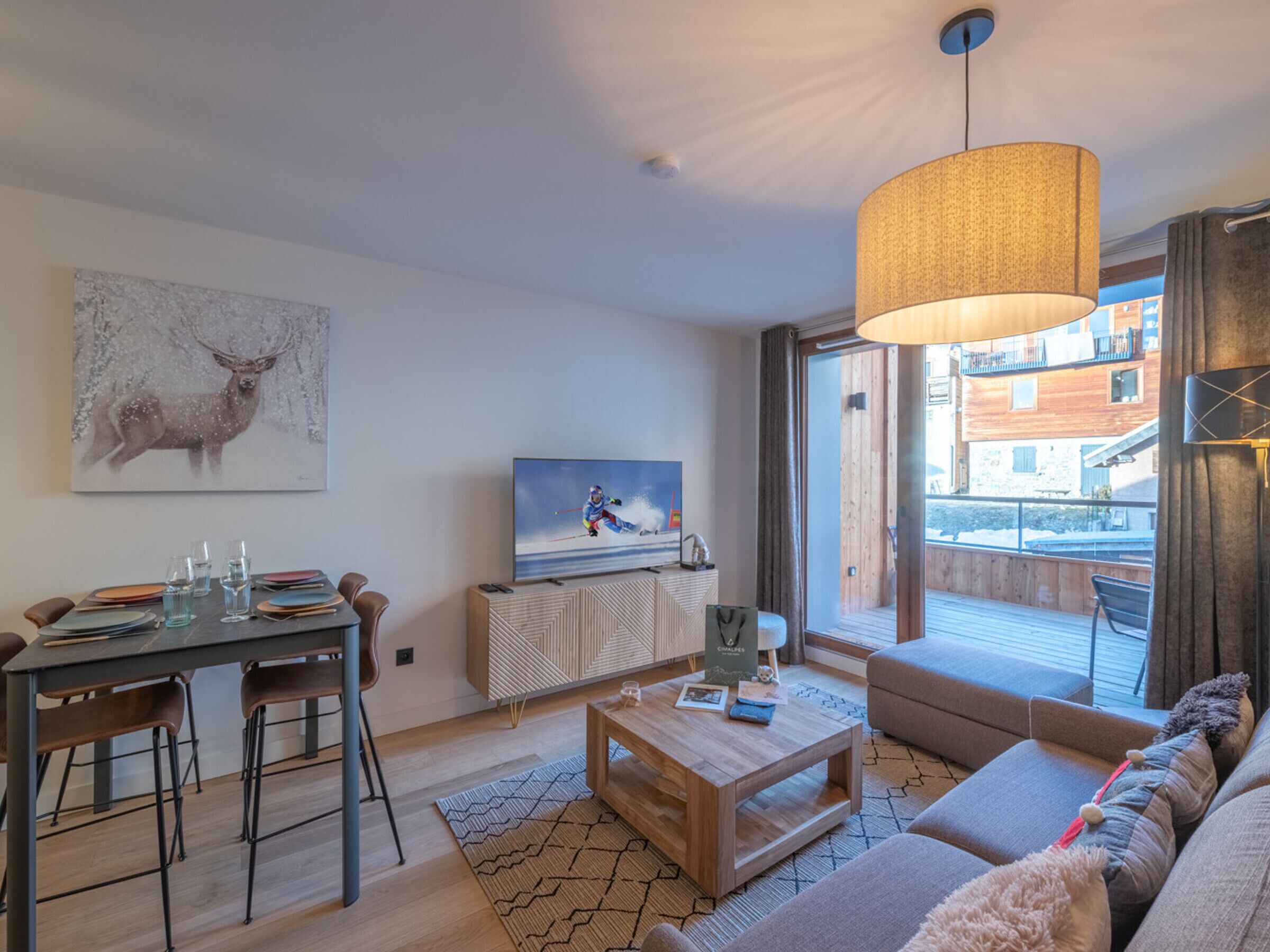 A modern living room with a dining area, a large window with a view of buildings, a painting of a deer, and a television.