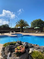 Una piscina al aire libre de temporada, sombrillas, tumbonas