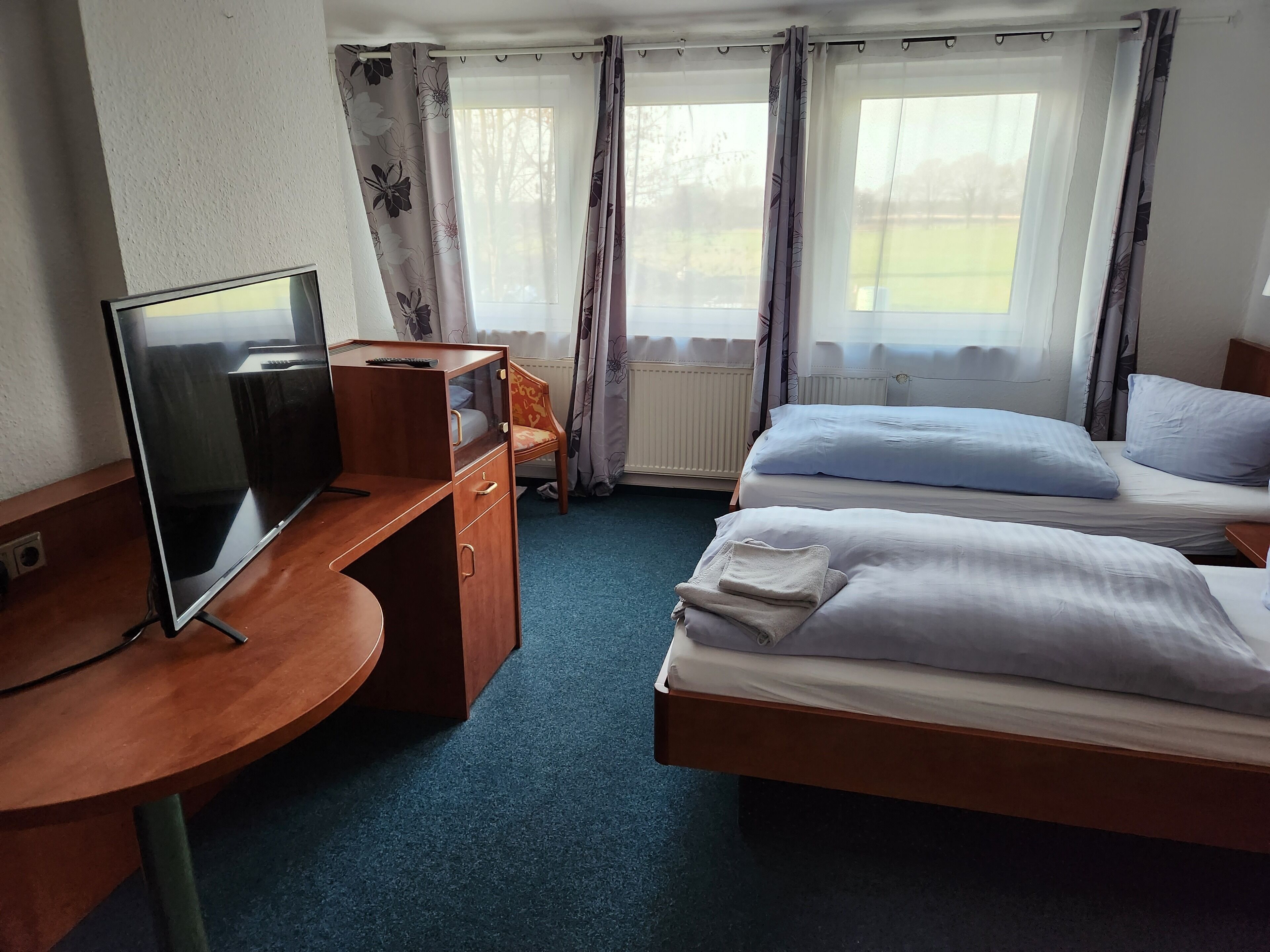 A hotel room with a desk, a bed, and a television.