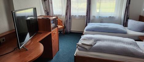 Ein Hotelzimmer mit Schreibtisch, Bett und Fernseher.