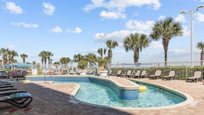 A pool area with multiple pools, sun loungers, and palm trees.