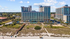 A multi-story hotel with a pool area, surrounded by greenery and a beach. - Oceanview at Dunes Village | 4 Beds & Waterpark (Myrtle Beach)