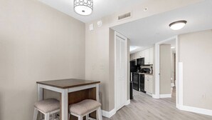 A modern kitchen with white cabinets, a black stove, and a wooden dining table with two chairs. - Oceanview at Dunes Village | 4 Beds & Waterpark (Myrtle Beach)