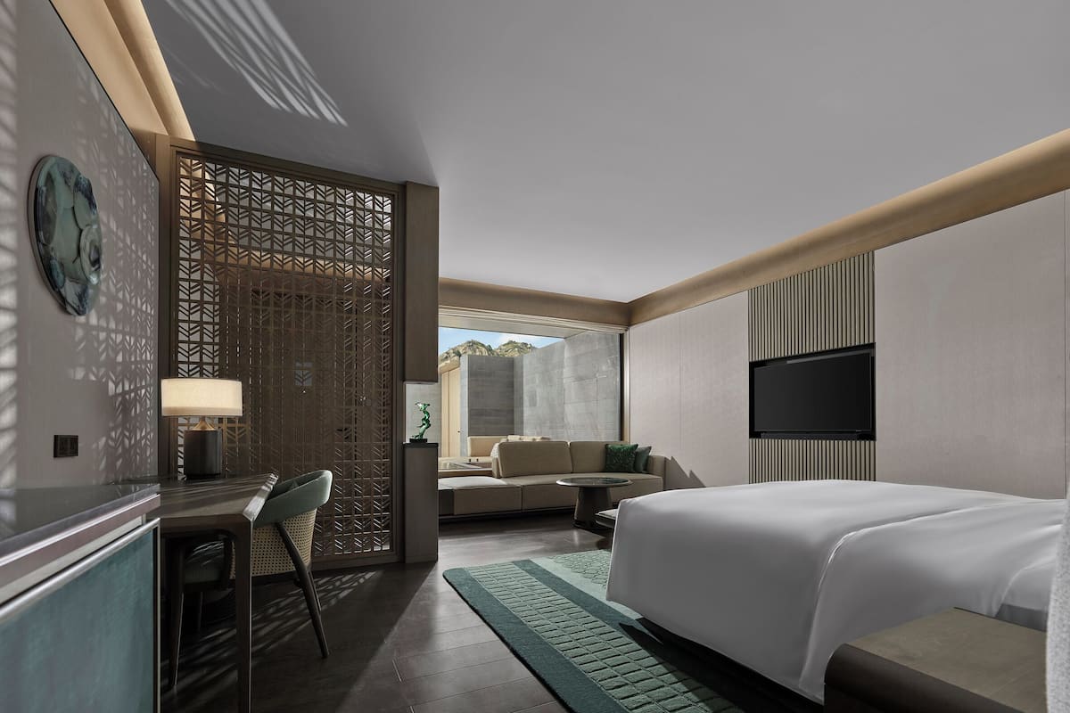 A modern hotel room with a bed, desk, and seating area.