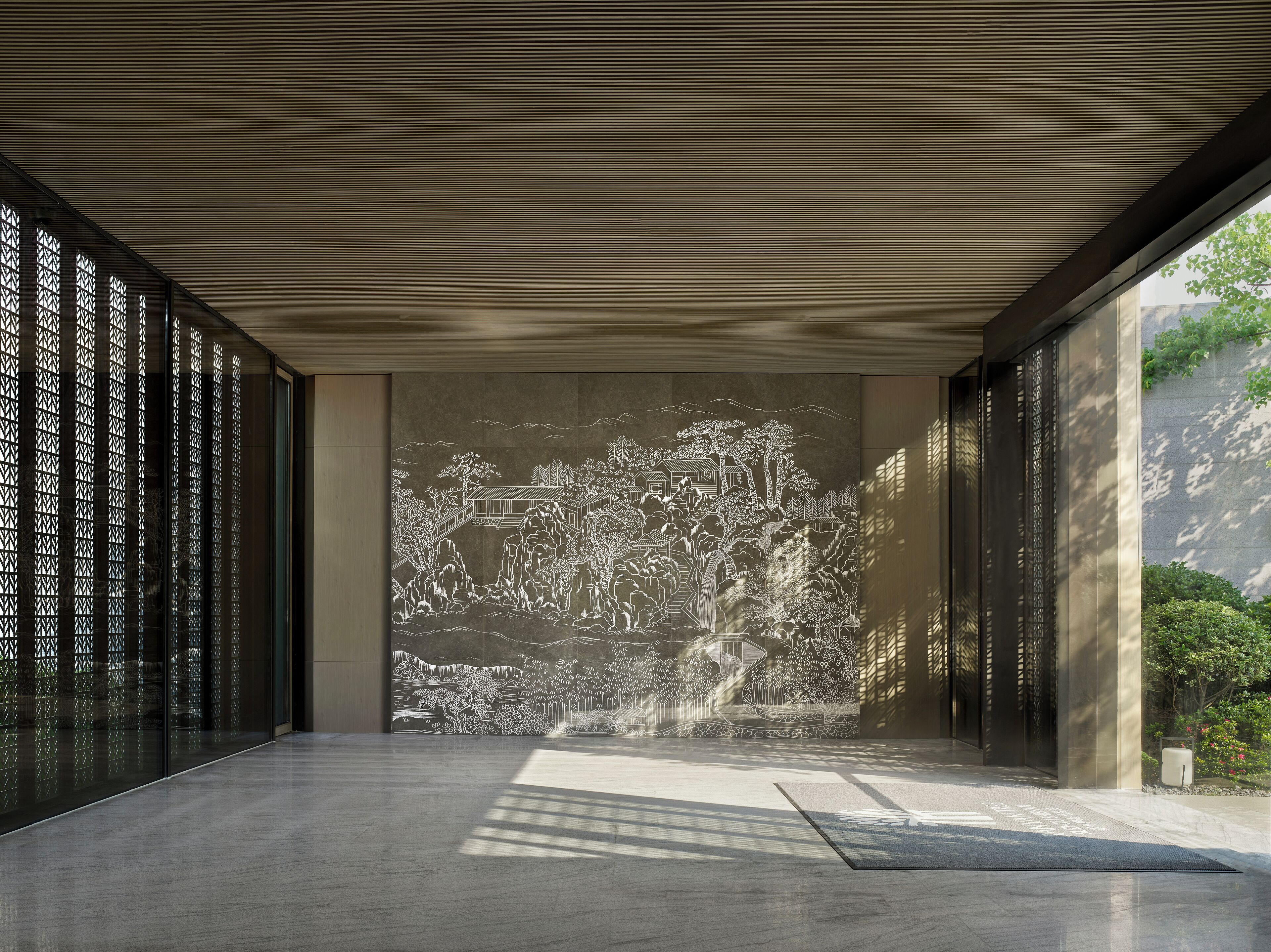 Un interior moderno con un gran mural que representa un paisaje tradicional, un techo inclinado y un suelo con un diseño geométrico.