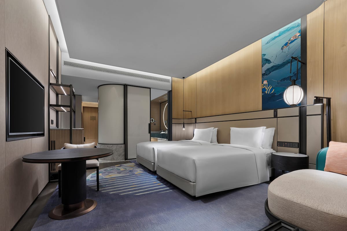 Una habitación de hotel moderna con una cama grande, un escritorio, una silla y un televisor.