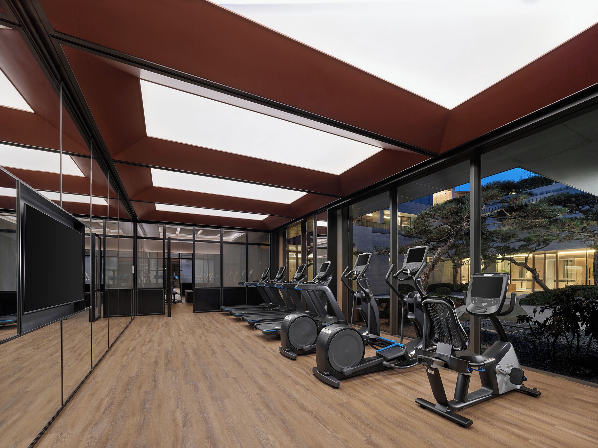 A modern gym with exercise equipment and large windows.