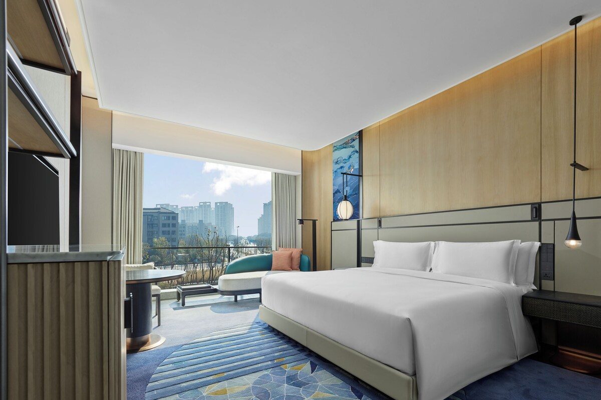 Una habitación de hotel moderna con una cama grande, un escritorio y vistas a la ciudad.
