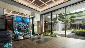 A modern gym with exercise equipment, a large glass wall, and a wooden floor. - Angsana Suzhou Shishan (Suzhou)