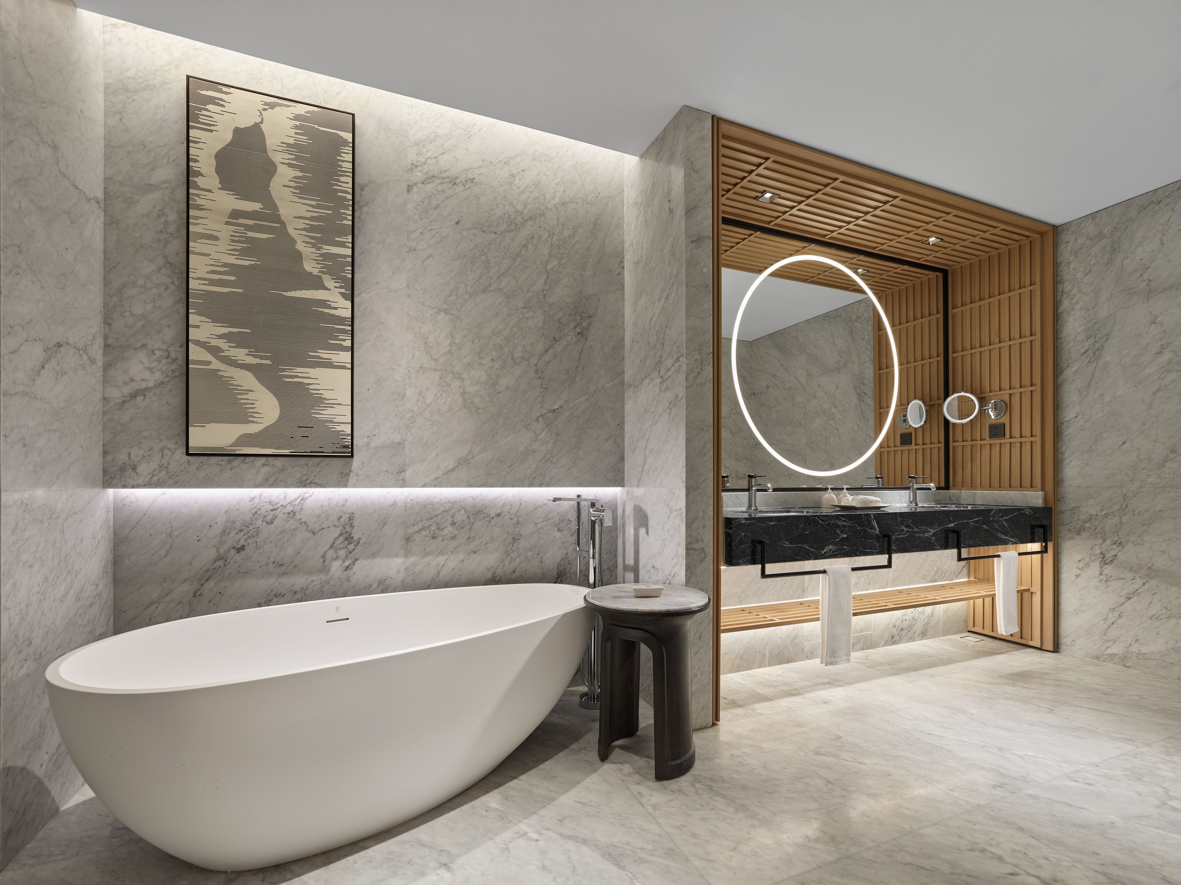 Un bagno moderno con una vasca freestanding, un mobile vanitario in legno con un grande specchio e una parete in marmo.