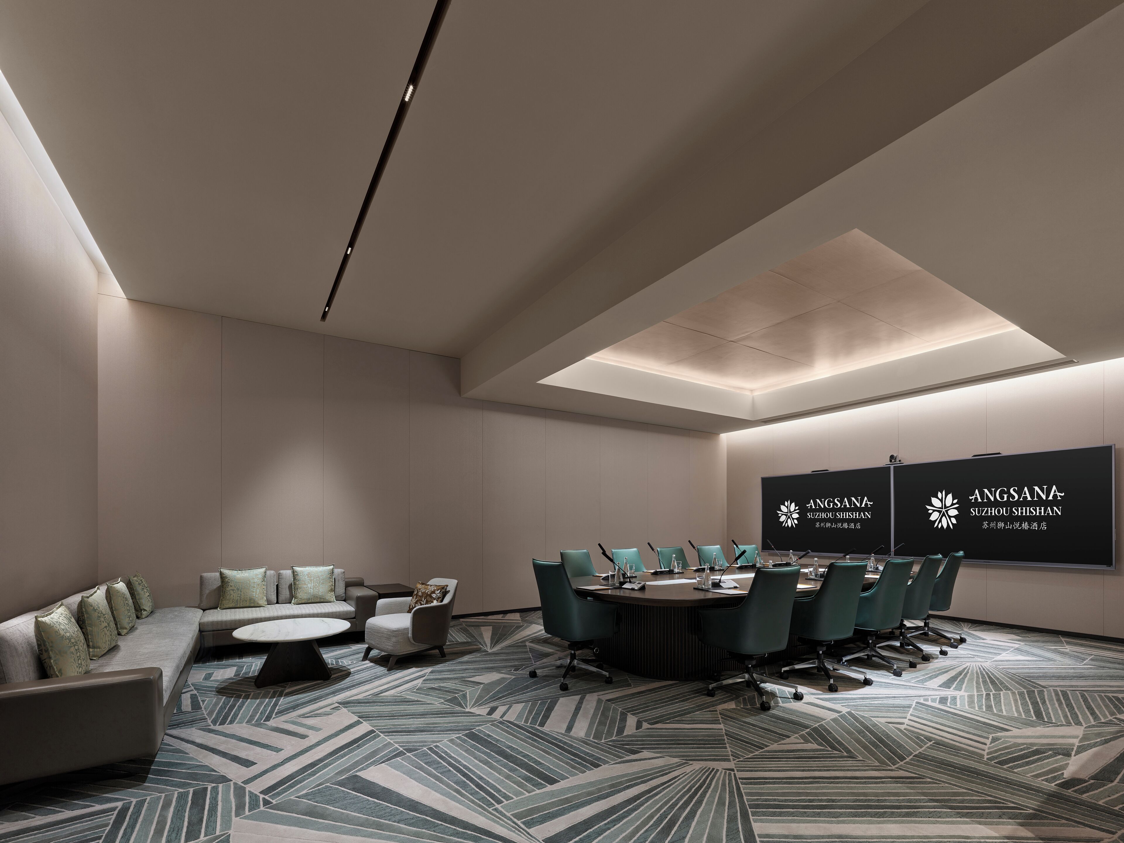 Une salle de conférence moderne, dotée d’une longue table, de plusieurs chaises, d’un canapé et d’un tapis à motifs.