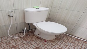 A toilet with a white tank and seat, a visible flush handle, and a water pipe. - OYO Life 92543 Ratu Sakti Residence Syariah (Semarang)