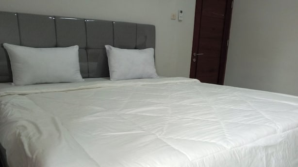 A neatly made bed with a grey headboard and white bedding. - OYO Life 92543 Ratu Sakti Residence Syariah (Semarang)