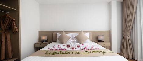 A neatly made bed with a welcome mat, two pillows, and a bedside table with a lamp.