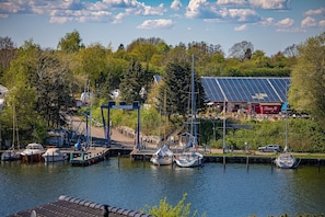 Boats docked at the marina, surrounded by lush greenery and a charming building with a solar panel array.