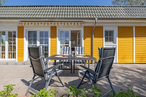 Relax on the patio with a black table and four comfortable chairs, surrounded by a beautiful view.