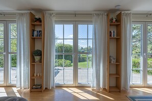 Enjoy the serene atmosphere in this stylish room with a sliding glass door leading to an outdoor area, a wooden bookshelf, and a clean, minimalist design.