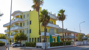 Un hotel de varios pisos con balcones, un letrero de restaurante y palmeras.