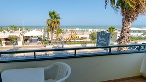 Un balcón con vista a una playa, un cartel del Hotel Roma y un parque infantil al fondo.
