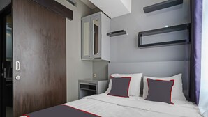 Una habitación de hotel moderna con una cama grande, una mesita de noche, un espejo y estantes integrados.