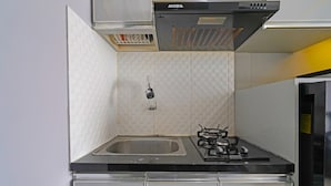 Una cocina compacta con estufa a gas, pileta de acero inoxidable y una campana extractora moderna.