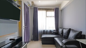 Una sala de estar moderna con una televisión de pantalla plana, un sofá y una mesita.