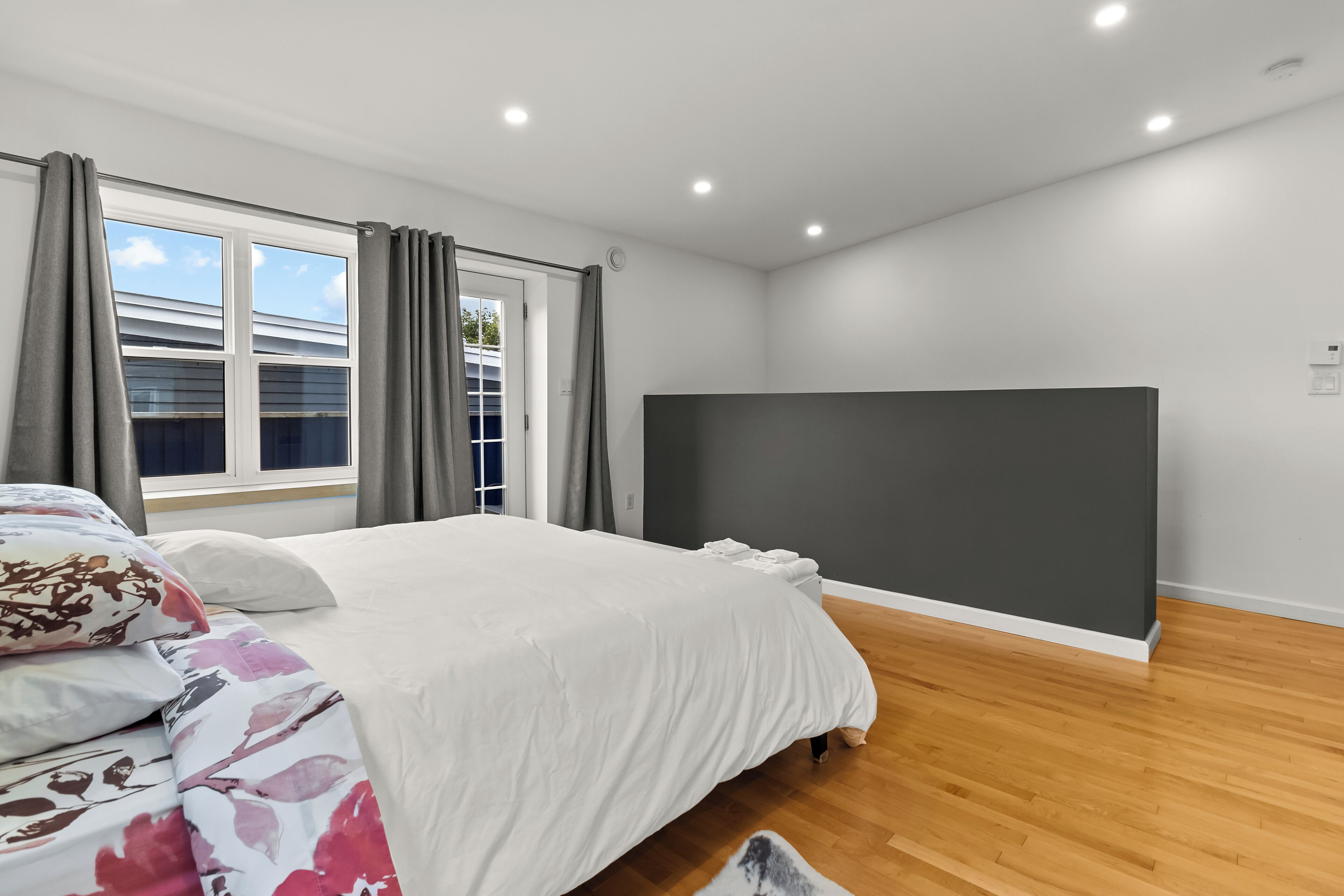 Une chambre à coucher avec un lit, des rideaux, une fenêtre et un mur de couleur sombre.