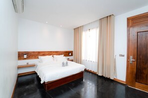 A modern bedroom with a wooden headboard, a large bed, a bedside table, and a window with curtains. - UMA Residence (Siem Reap)