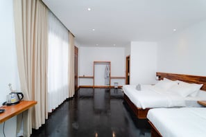Une chambre d’hôtel avec un lit en bois, une table de chevet avec une bouilloire et une grande fenêtre avec des rideaux.