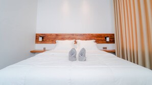 A neatly made bed with white linens and gray slippers placed on the footboard. - UMA Residence (Siem Reap)