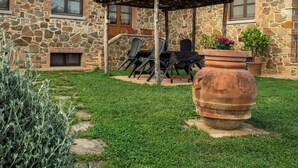 Una casa de piedra con un patio, mobiliario exterior y una maceta grande.