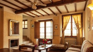 Una sala de estar acogedora con chimenea, vigas de madera, una mesa de comedor y un sofá.