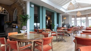 A spacious dining area with high ceilings, large windows, and orange upholstered chairs. - Hotel Victoria (Whitby)