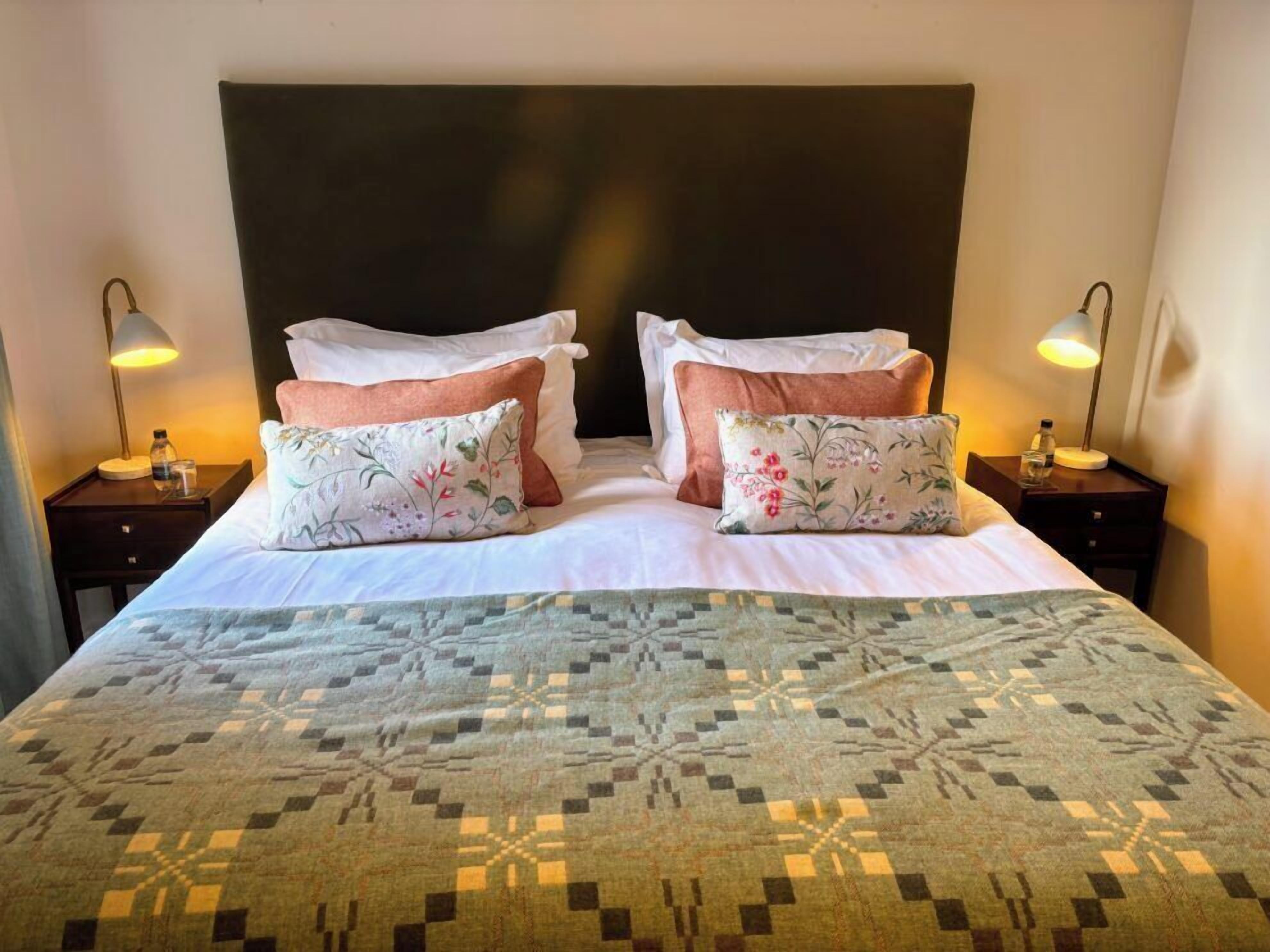 A hotel room with a large bed, two nightstands, and two lamps.