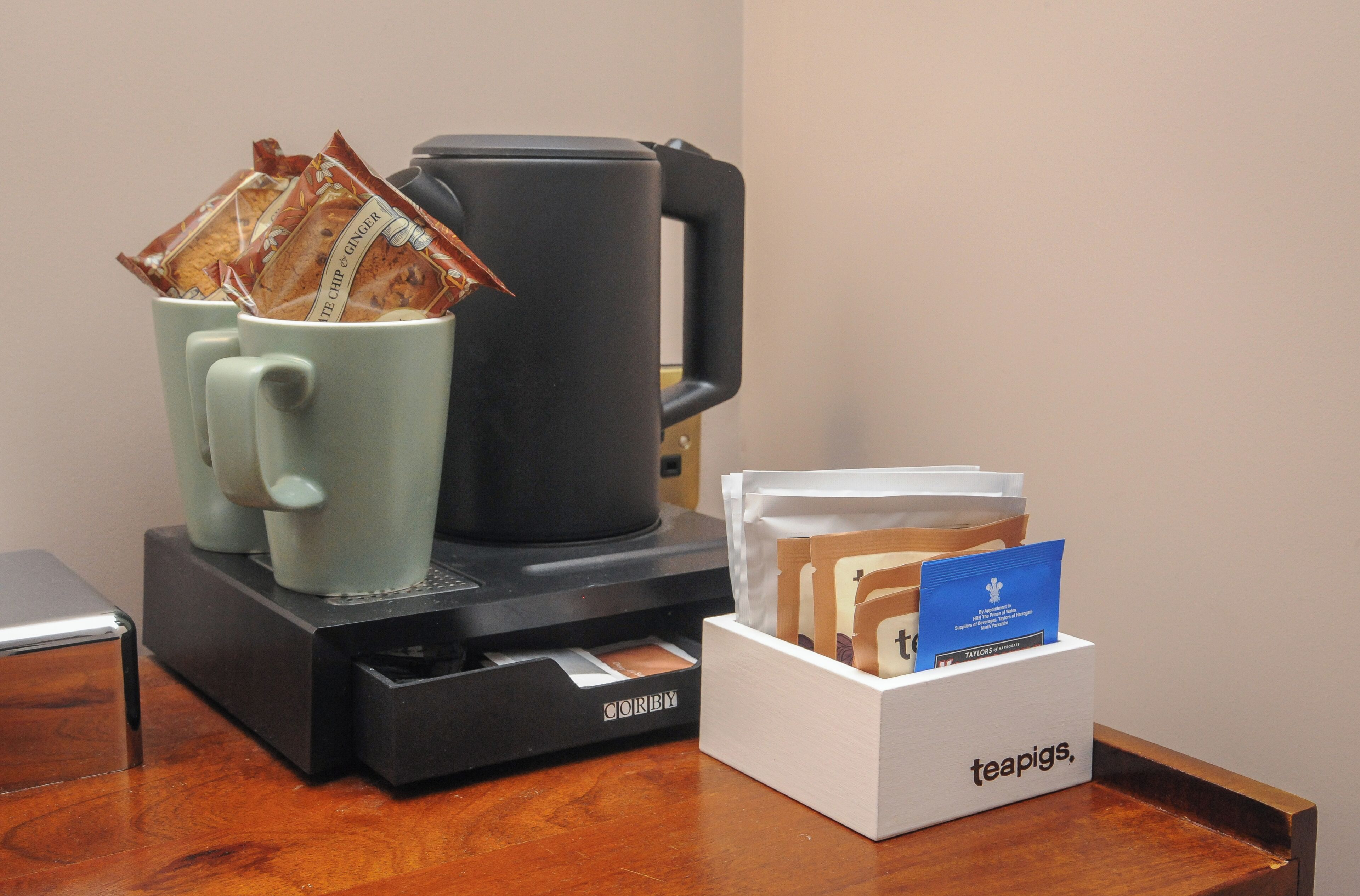 A coffee machine with a teabag holder and a card holder on a wooden table.