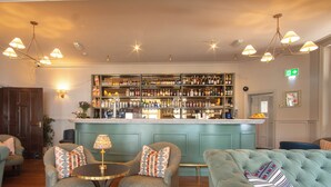 A bar area with a wooden floor, bar counter, and seating with patterned cushions. - Hotel Victoria (Whitby)