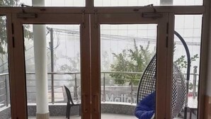 A glass door entrance to a covered outdoor area with a ceiling fan, a hanging chair, and a metal chair.