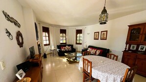 Ein geräumiges Wohnzimmer mit Essbereich, ausgestattet mit einem Holztisch, Stühlen, einer Couch und einem Couchtisch.