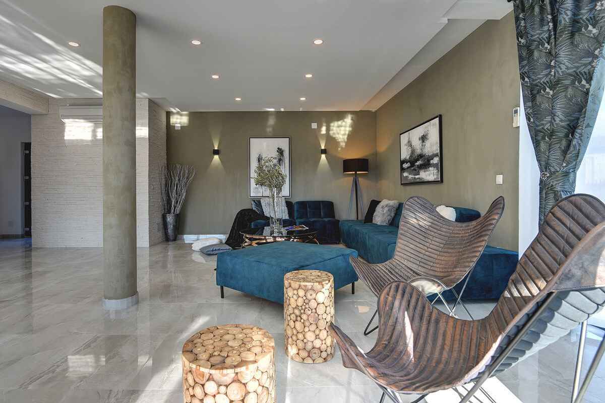 A spacious living area with a blue sofa, a wooden coffee table, and a modern chair.